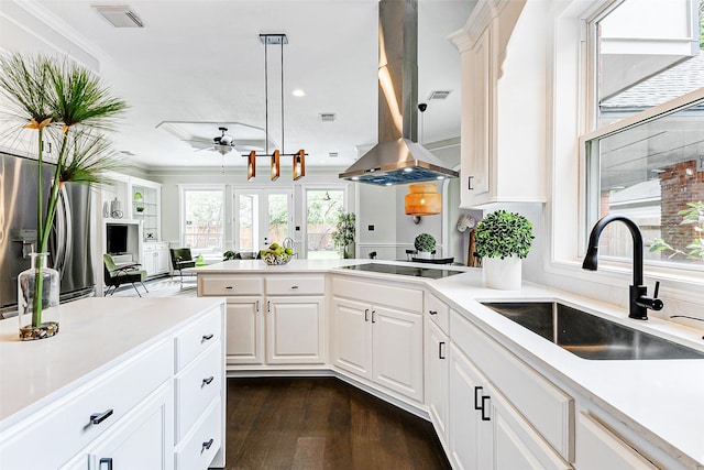 kitchen featuring a sink, island range hood, black electric cooktop, light countertops, and ornamental molding
