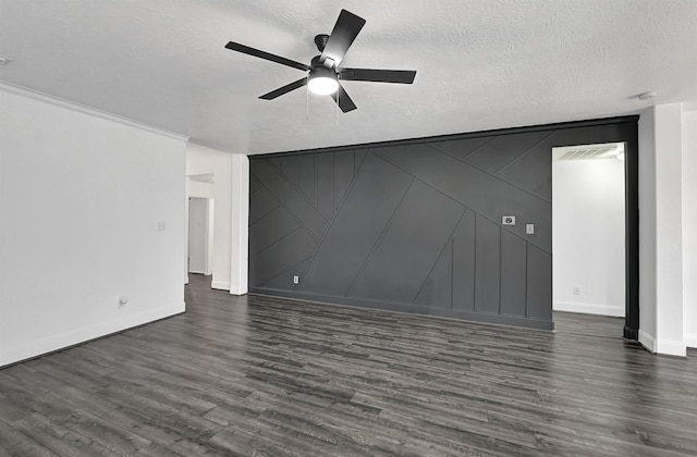 unfurnished living room with a textured ceiling, dark wood-style flooring, baseboards, ceiling fan, and a decorative wall