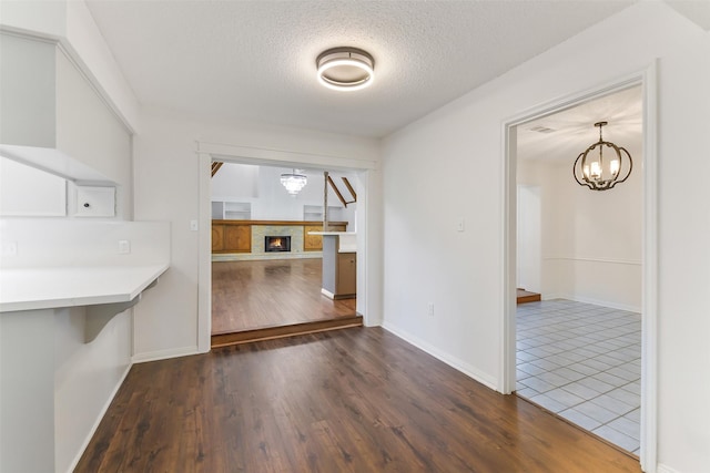 unfurnished dining area with an inviting chandelier, baseboards, a textured ceiling, and dark wood finished floors