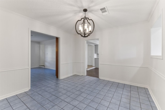 empty room with tile patterned floors, a textured ceiling, visible vents, a notable chandelier, and crown molding