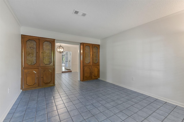 unfurnished room featuring a textured ceiling, light tile patterned floors, visible vents, a chandelier, and ornamental molding