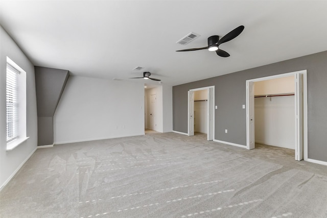 unfurnished bedroom featuring carpet flooring, baseboards, visible vents, and two closets