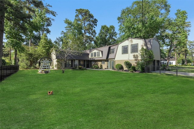 view of front of property with fence, a gambrel roof, and a front yard