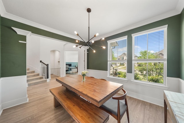 dining space featuring arched walkways, a wainscoted wall, stairs, and a notable chandelier