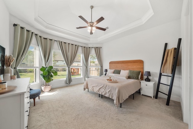 bedroom with light carpet, baseboards, a raised ceiling, and multiple windows