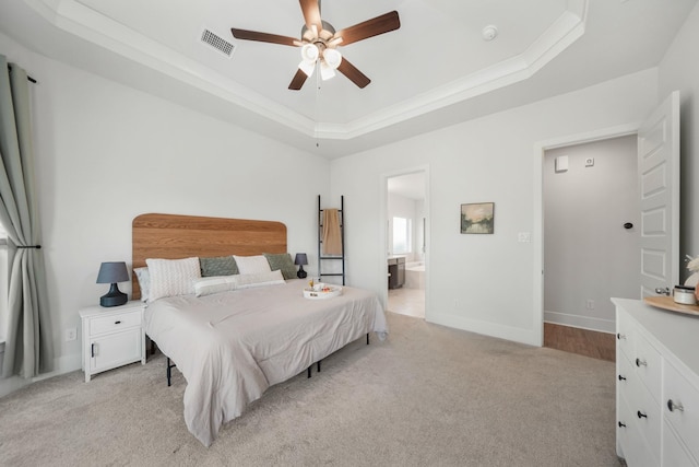 bedroom featuring ensuite bathroom, ceiling fan, a raised ceiling, light colored carpet, and visible vents