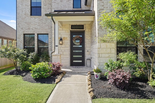 property entrance with brick siding, stone siding, and fence