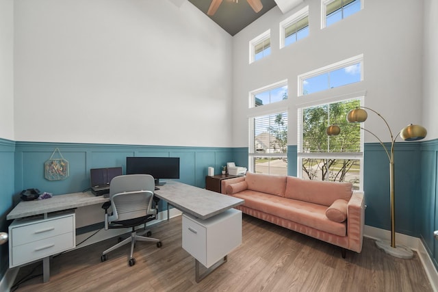 office featuring high vaulted ceiling, a ceiling fan, wainscoting, and wood finished floors