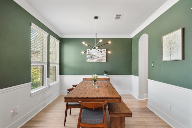 dining room featuring arched walkways, visible vents, a notable chandelier, wood finished floors, and crown molding