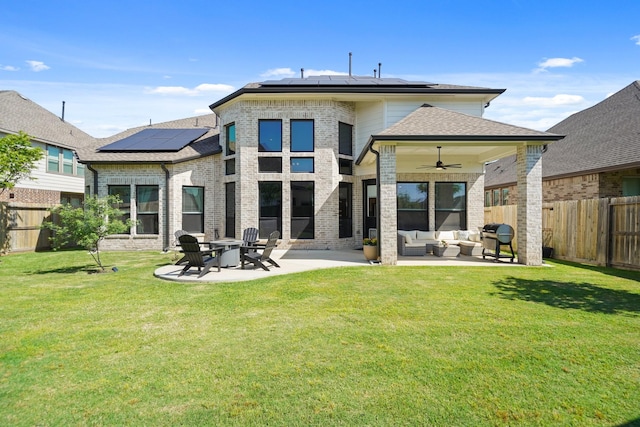 rear view of house featuring a ceiling fan, outdoor lounge area, a yard, solar panels, and a patio