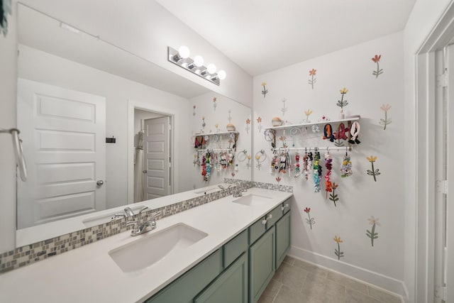 bathroom with double vanity, baseboards, and a sink