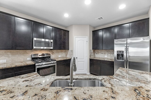 9974 Stone Creek Ln, Brookshire, TX 77423 - kitchen with stainless steel appliances, a sink, light stone counters, recessed lighting, and decorative backsplash
