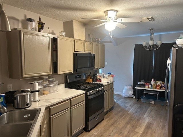 kitchen featuring gas range, black microwave, a sink, ceiling fan, and a textured ceiling