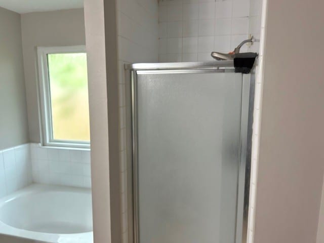 bathroom featuring a stall shower, a garden tub, and plenty of natural light