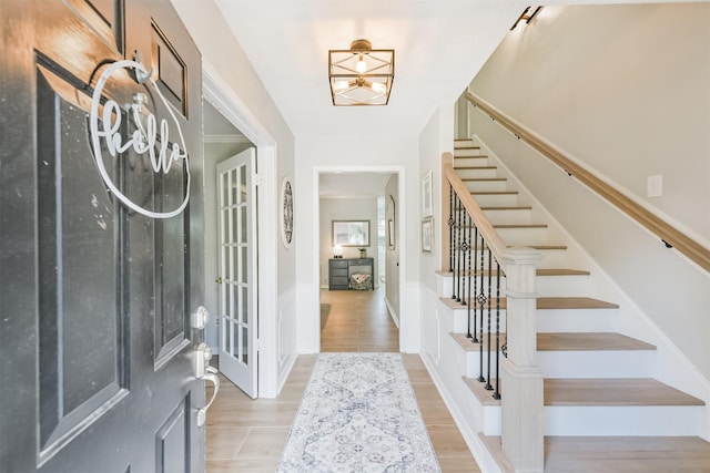 foyer with baseboards, wood finished floors, and stairs