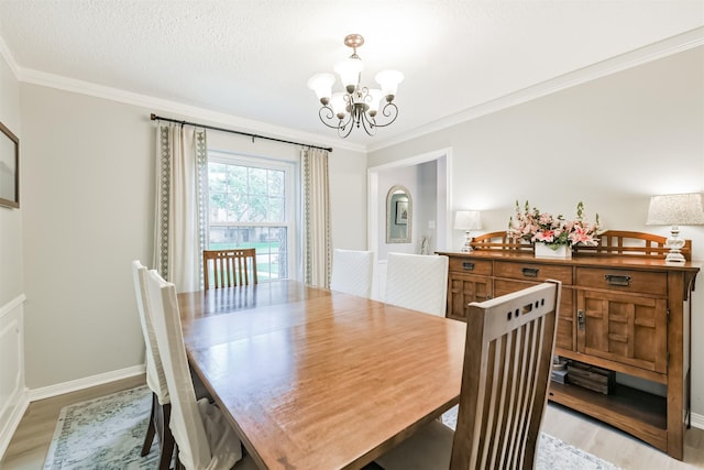 dining area featuring ornamental molding, baseboards, a notable chandelier, and light wood finished floors