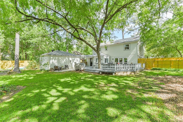 back of property with a fenced backyard, a wooden deck, and a lawn