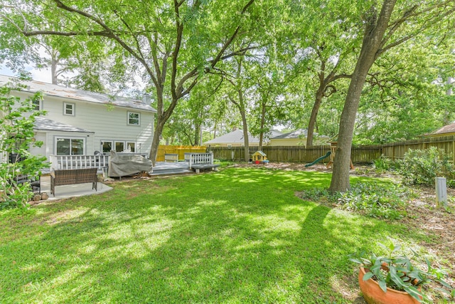 view of yard featuring a fenced backyard, a playground, and a deck