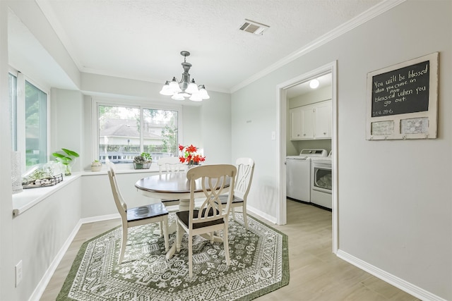 dining space with light wood finished floors, a textured ceiling, washing machine and dryer, visible vents, and a notable chandelier