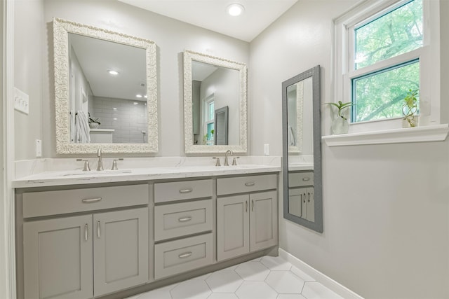 bathroom with tile patterned flooring, a sink, double vanity, and tiled shower