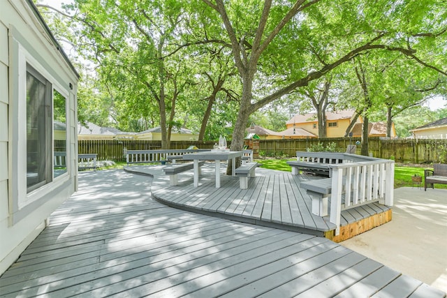 wooden terrace with a fenced backyard and outdoor dining space