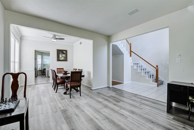 dining room with light wood-style floors, stairs, ceiling fan, baseboards, and ornamental molding