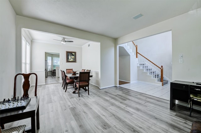 dining room featuring light wood finished floors, stairs, a ceiling fan, and baseboards