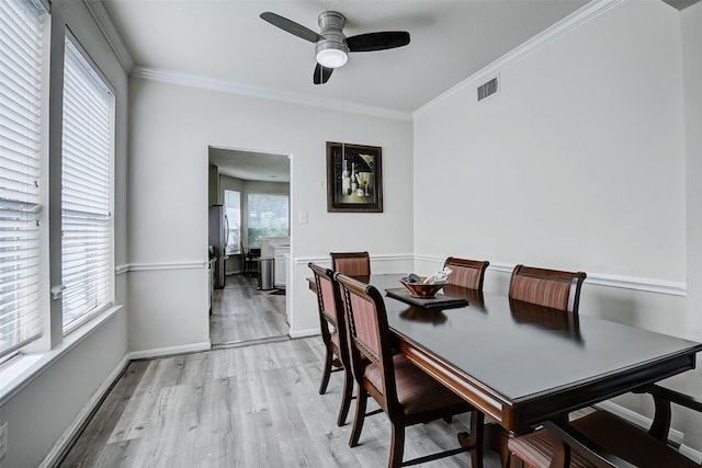 dining room with crown molding, a ceiling fan, light wood-style flooring, and baseboards