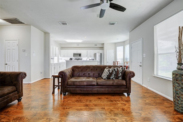 living area with wood finished floors, ceiling fan, and baseboards