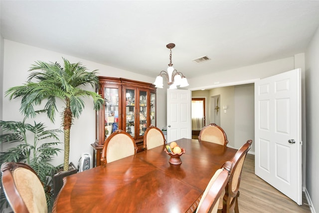 dining space with visible vents, light wood-style flooring, and a notable chandelier