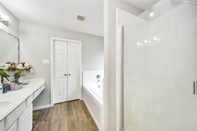 bathroom featuring wood finished floors, a stall shower, a bath, visible vents, and vanity