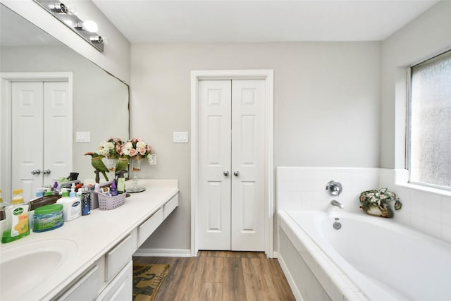 full bath with a closet, wood finished floors, vanity, and a garden tub
