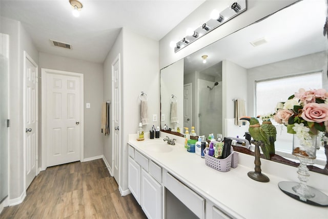 full bathroom featuring wood finished floors, visible vents, baseboards, walk in shower, and vanity