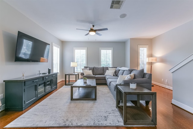 living area with a ceiling fan, baseboards, visible vents, and wood finished floors