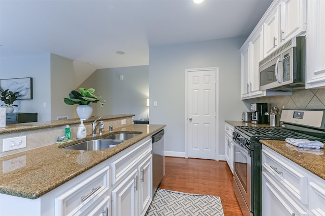 kitchen with tasteful backsplash, wood finished floors, a sink, white cabinets, and stainless steel appliances