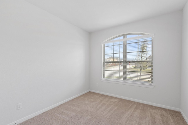 empty room with plenty of natural light, baseboards, and light colored carpet