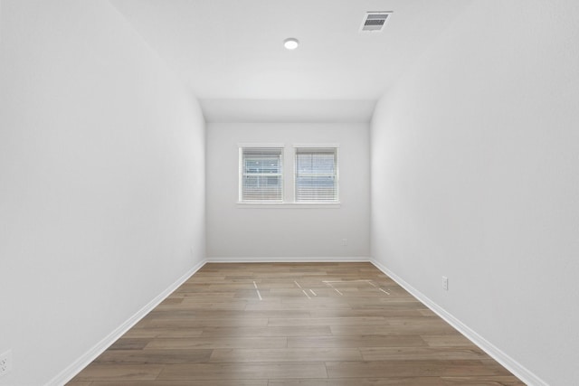 unfurnished room featuring baseboards, wood finished floors, and visible vents