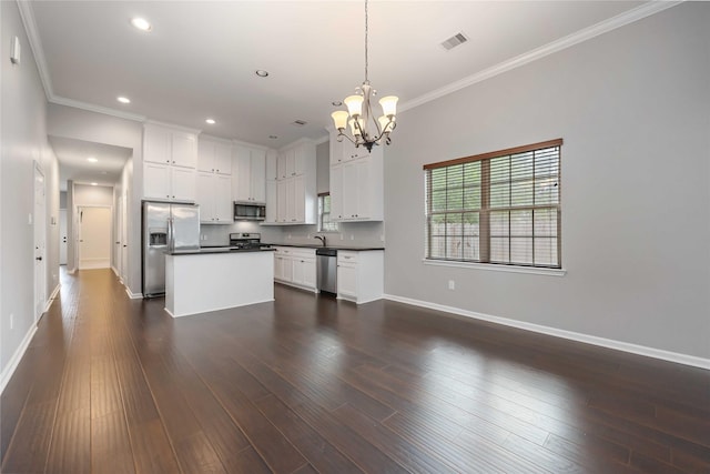 kitchen with an inviting chandelier, crown molding, visible vents, dark countertops, and appliances with stainless steel finishes