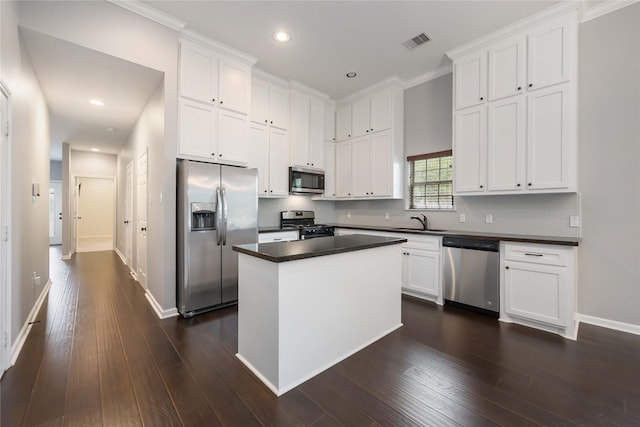 kitchen with visible vents, dark countertops, white cabinetry, a sink, and stainless steel appliances
