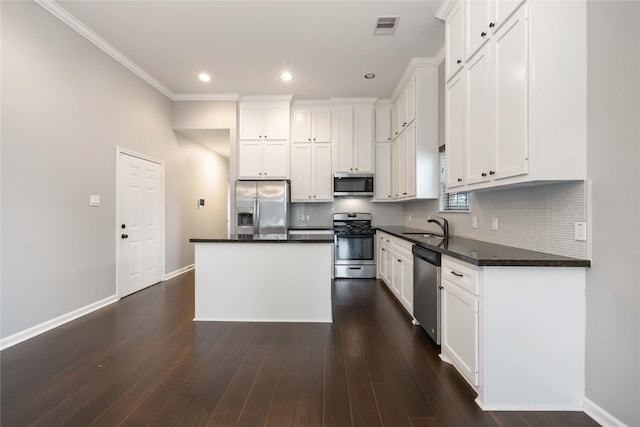 kitchen featuring visible vents, appliances with stainless steel finishes, dark countertops, a sink, and baseboards