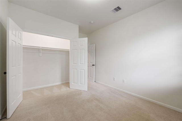 unfurnished bedroom featuring baseboards, visible vents, a closet, and light colored carpet