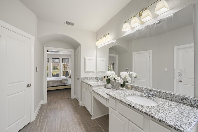 ensuite bathroom featuring vanity, ceiling fan, baseboards, ensuite bath, and visible vents