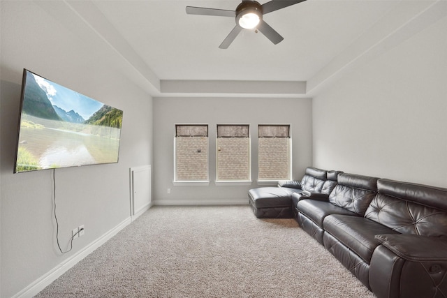 living room with a ceiling fan, baseboards, carpet floors, and a raised ceiling
