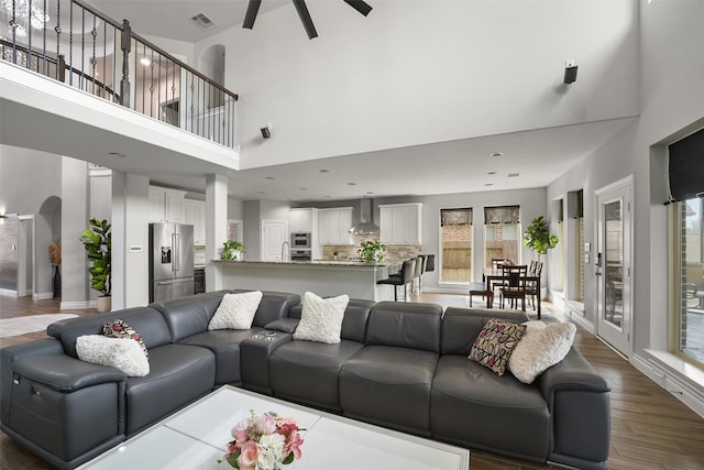 living room featuring a towering ceiling, wood finished floors, visible vents, and a wealth of natural light