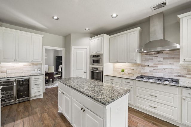 kitchen featuring white cabinets, stainless steel appliances, wine cooler, wall chimney range hood, and dark wood-style flooring