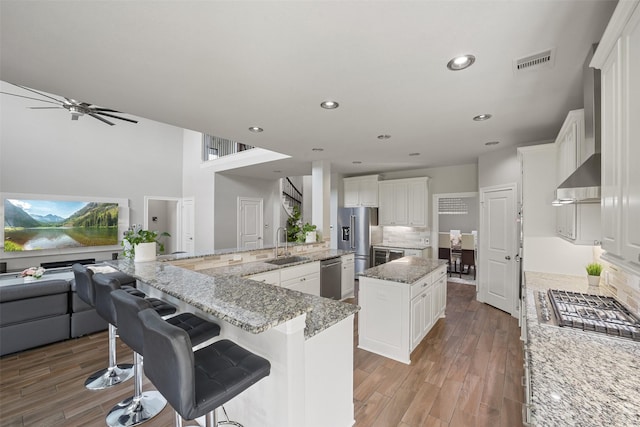 kitchen with a spacious island, light wood finished floors, stainless steel appliances, and visible vents