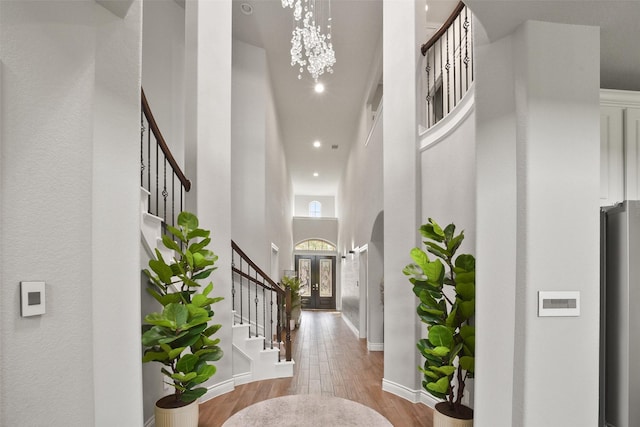 entrance foyer with recessed lighting, stairway, a towering ceiling, an inviting chandelier, and wood finished floors