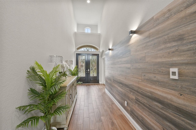 interior space featuring wood finished floors, wood walls, french doors, and a towering ceiling