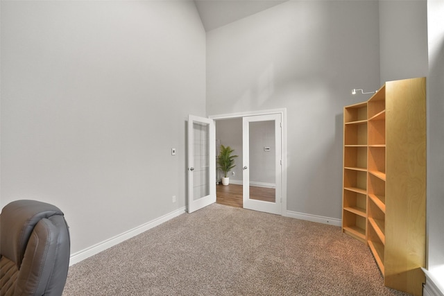 unfurnished office featuring baseboards, carpet floors, high vaulted ceiling, and french doors