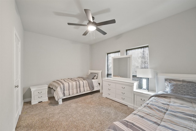 bedroom featuring light carpet, a ceiling fan, and baseboards